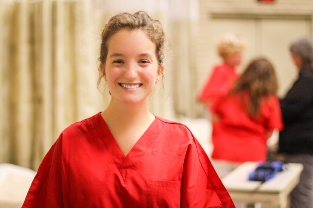 Girl in red scrubs smiling at the camera.