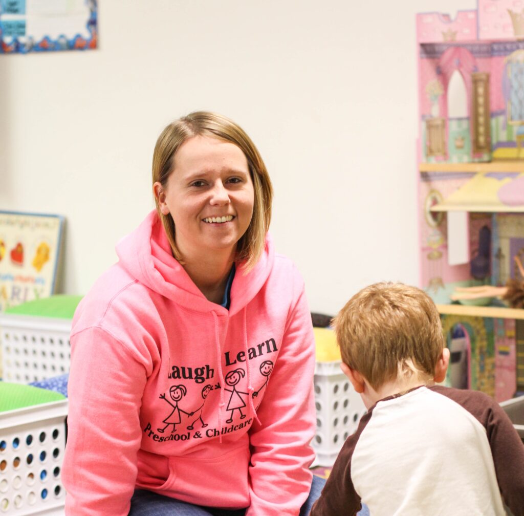 Woman smiling at the camera while caring for a child.