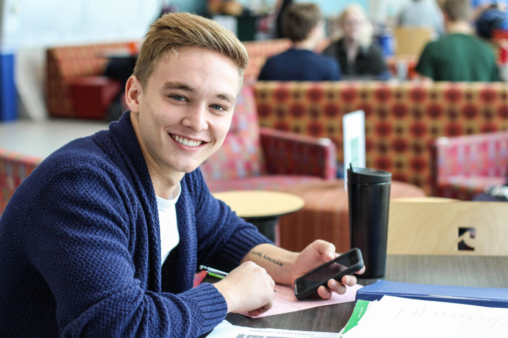 Smiling student on phone at table