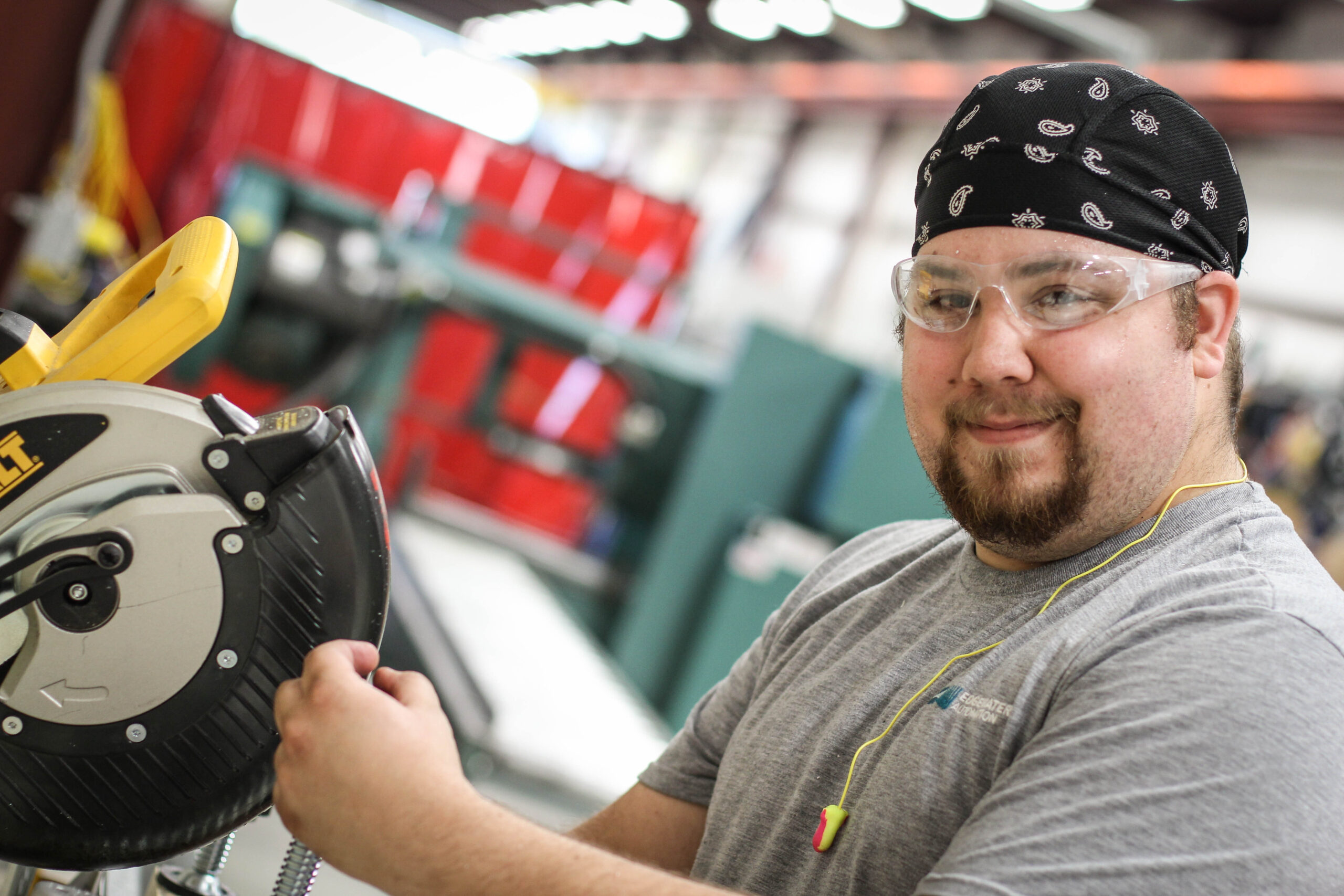 Man using a power saw while smiling at camera.