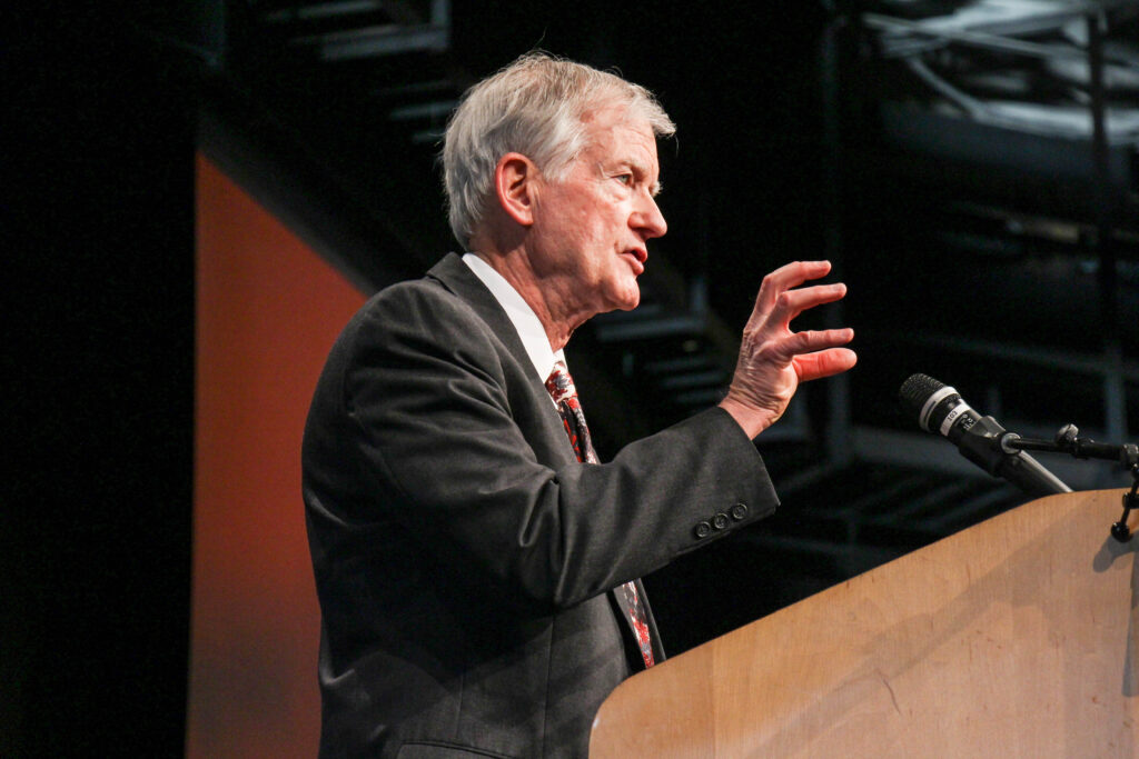 Man in suit speaking into a microphone.