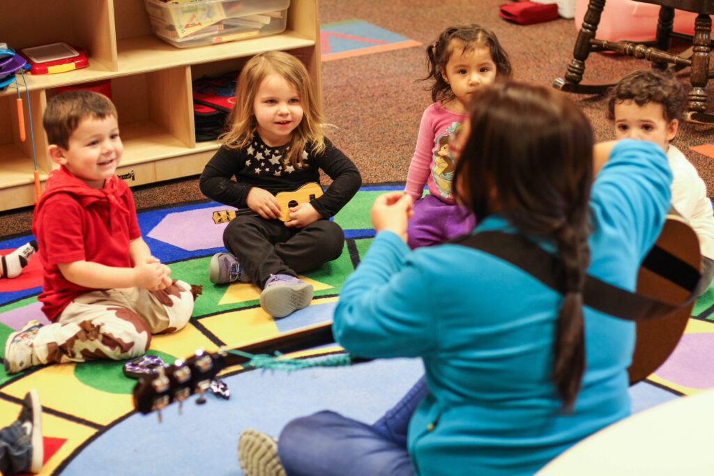 Woman playing guitar for the classroom.