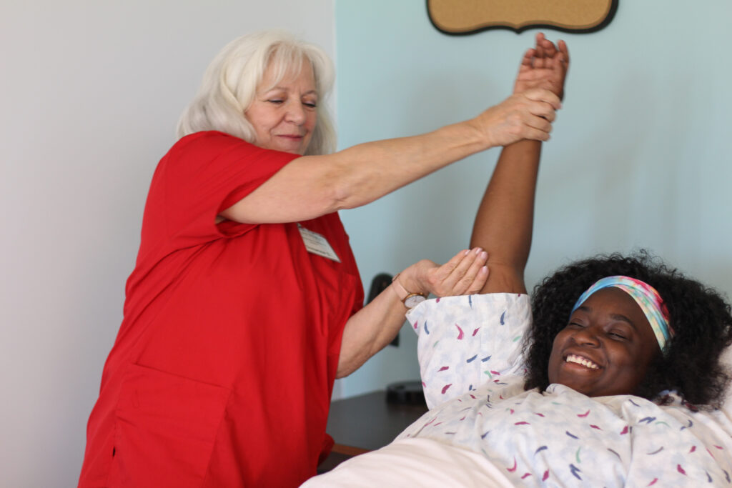 Health care worker helping to lift a woman's arm.