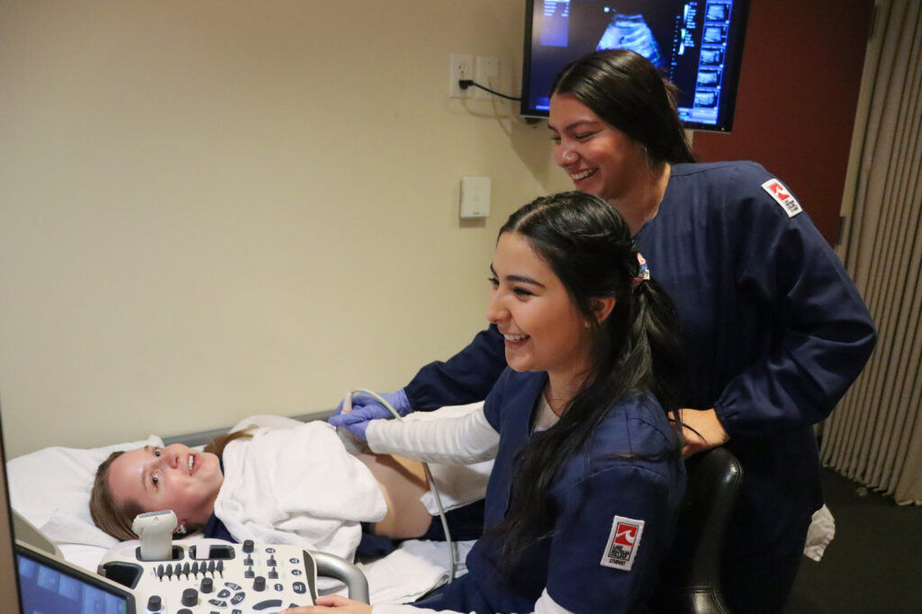 Two nursing students taking an X-Ray of a woman.