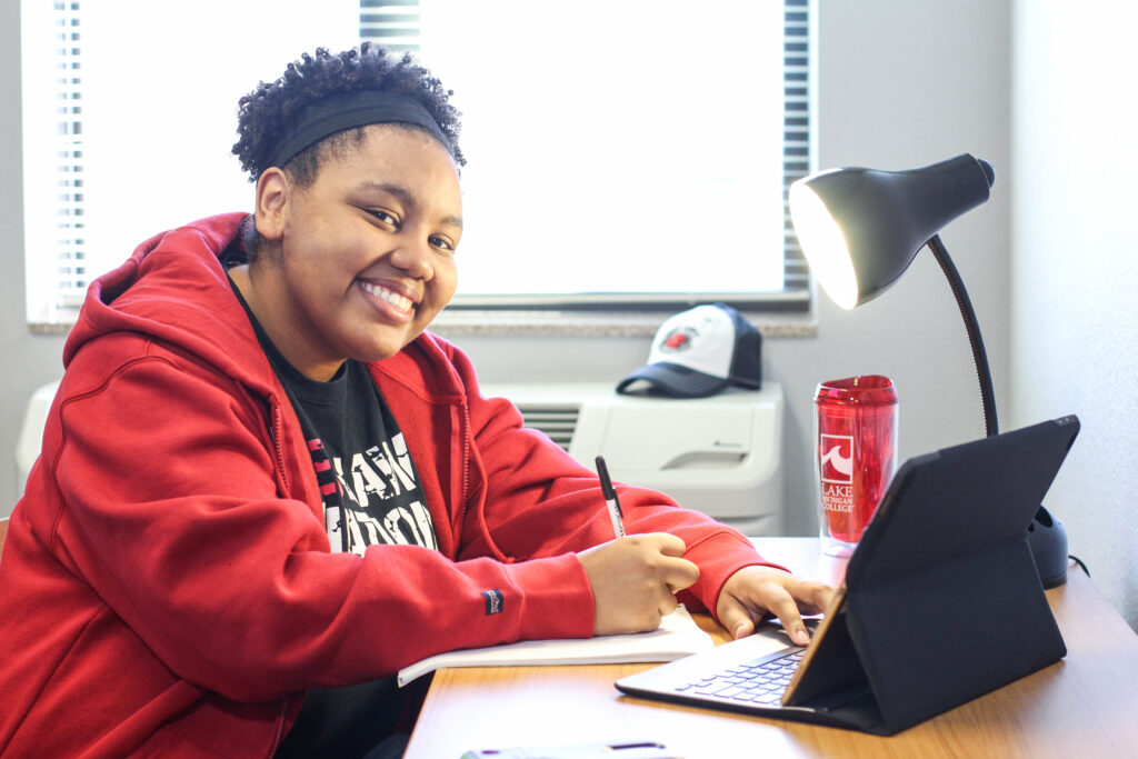 Smiling college girl working at a desk with tablet