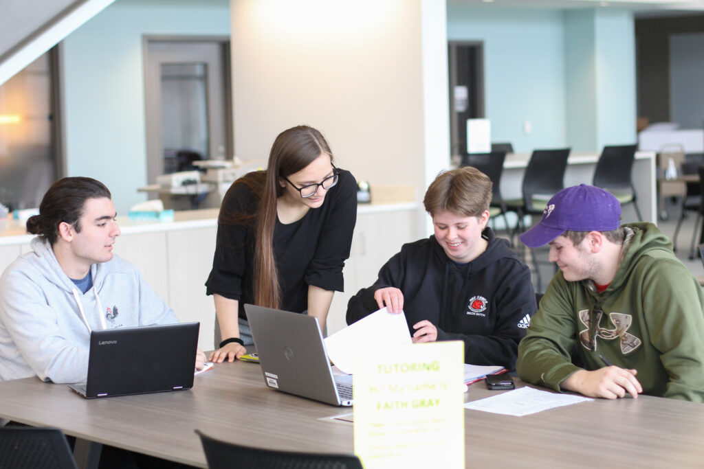 Several students studying with laptops around a table