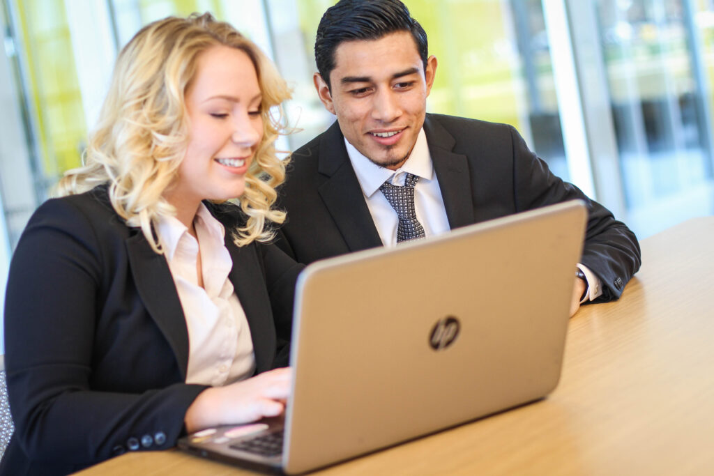 Man and woman in business clothes looking at laptop together
