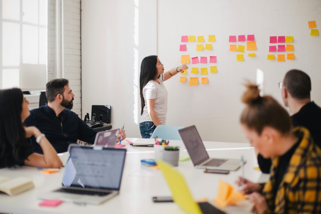 Group of business people around table watching woman present on a whiteboard