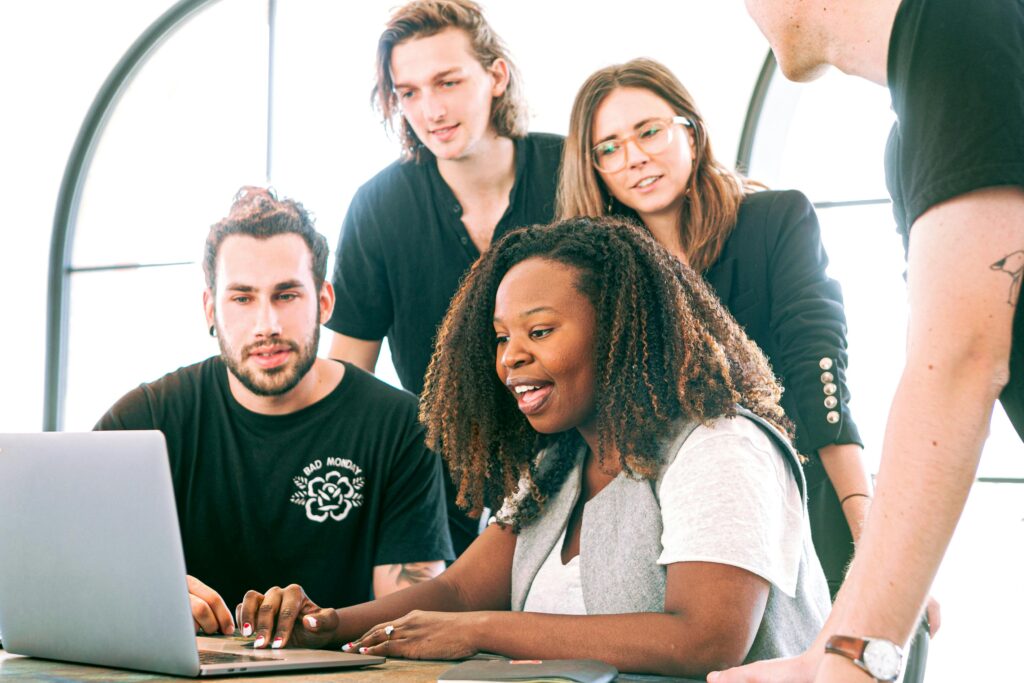 Several people grouped around computer and smiling