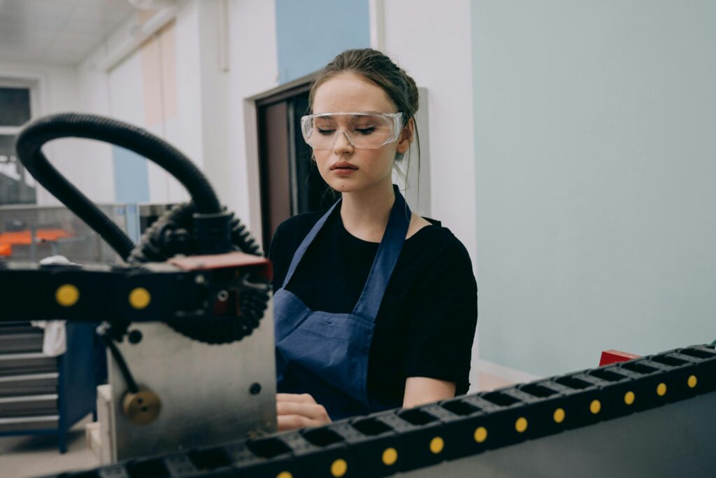 Woman in safety glasses working on machine